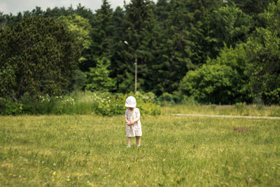 Boy standing on grass against trees