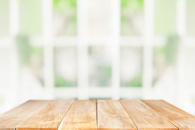 Close-up of wooden table against window