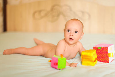 Portrait of cute baby boy lying on bed at home