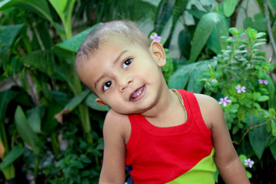  two years old kid laughing with open mouth and wearing colorful vest seating in home garden