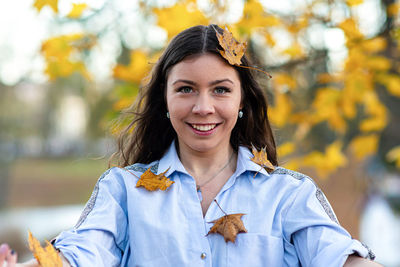 Portrait of smiling young woman with autumn leaves