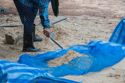 Low section of person cleaning sand at beach