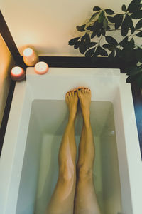 Low section of woman relaxing in bathtub 