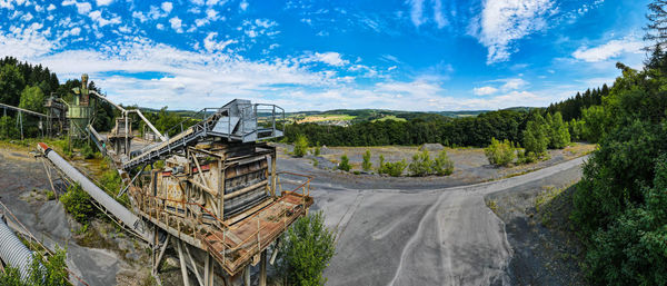 Panoramic shot of road amidst trees against sky
