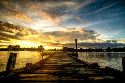 Pier over lake against sky during sunset