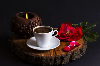 Close-up of roses in cup on table against black background