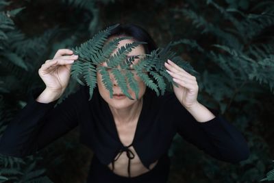 Woman with fern leaf in forest