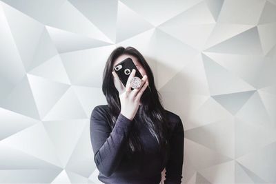 Portrait of young woman standing against wall