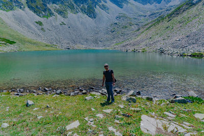 Full length of man standing at lakeshore against mountains