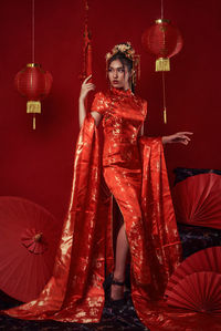 Full length portrait of woman standing against illuminated red background