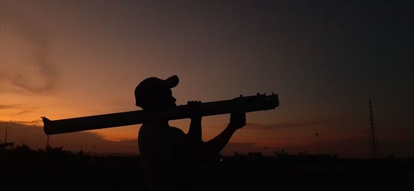 Silhouette man standing on field against sky during sunset