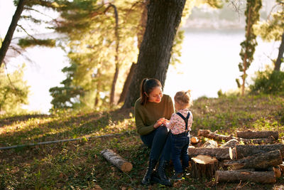 Side view of young man sitting on tree trunk