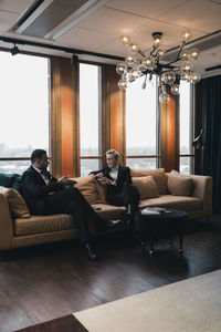 Male and female colleagues discussing strategy while sitting on sofa in office