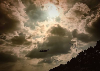 Low angle view of airplane flying against cloudy sky