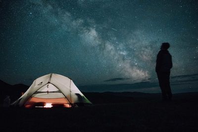 Rear view of man standing against sky at night