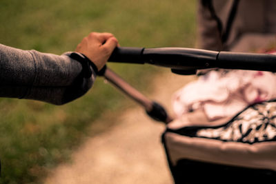 Cropped hand pushing baby stroller outdoors