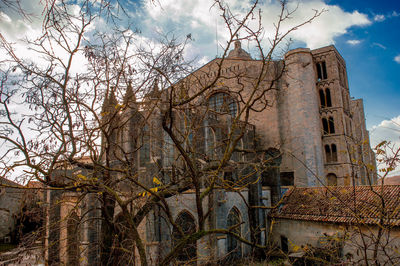 Bare trees by historic building against sky
