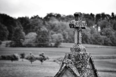 Close-up of cross on field against sky