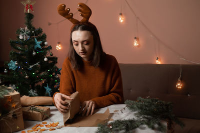 Portrait of young woman with christmas tree at home