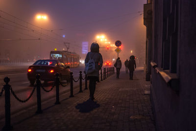 Rear view of person walking on footpath at night