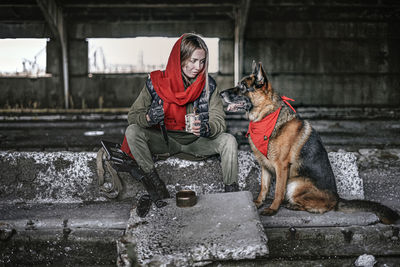 Rear view of woman with dog sitting in rain