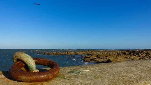 Rocks by sea against clear blue sky