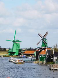 Traditional windmill by water against sky