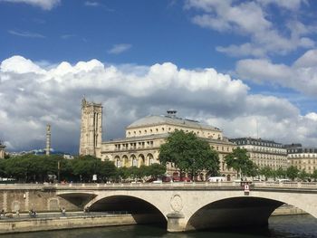 Arch bridge in city against cloudy sky