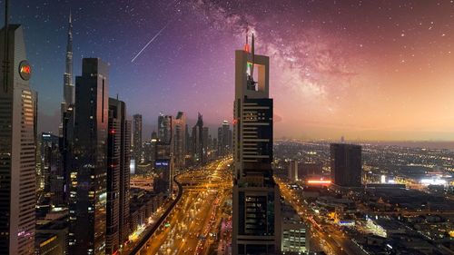Illuminated buildings in city against sky at night