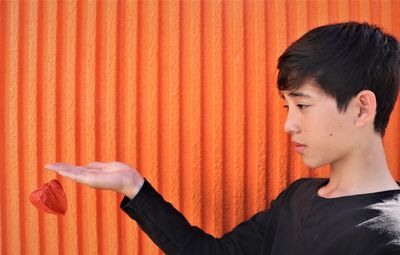 Boy holding leaf by orange wall