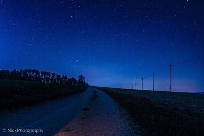 Road amidst field against sky at night