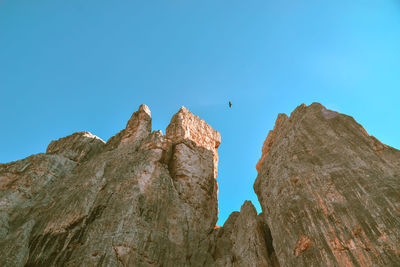 Low angle view of rock formation against clear blue sky