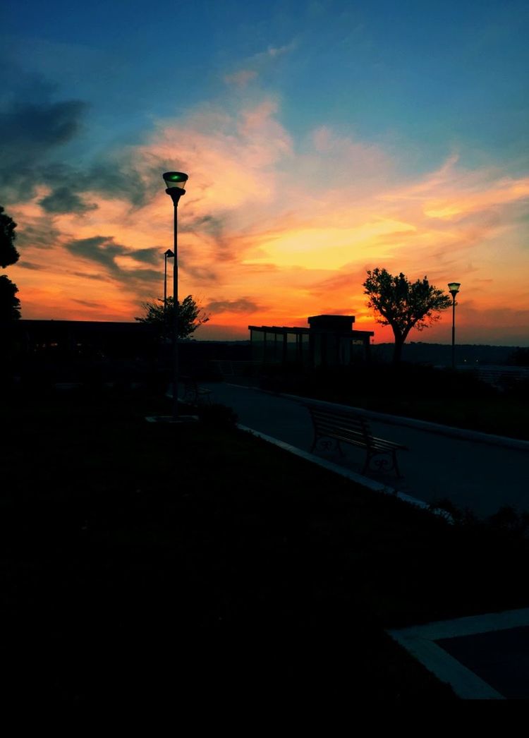 sunset, sky, silhouette, building exterior, tree, orange color, street light, architecture, built structure, cloud - sky, dusk, road, cloud, palm tree, street, nature, scenics, beauty in nature, city, outdoors