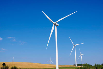 Low angle view of windmill on field against blue sky