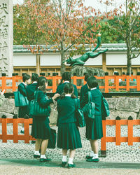 Rear view of people standing against building