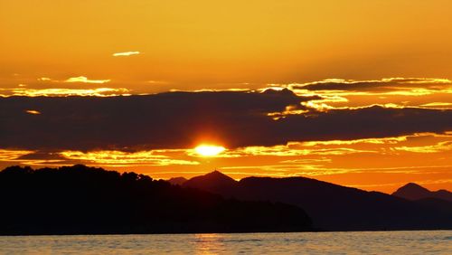 Scenic view of silhouette mountains against romantic sky at sunset