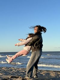 Rear view of woman standing on beach against clear sky