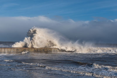 Waves splashing on sea against sky