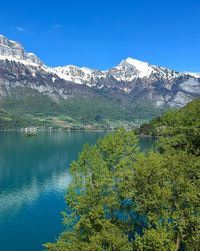 Scenic view of lake and mountains against blue sky