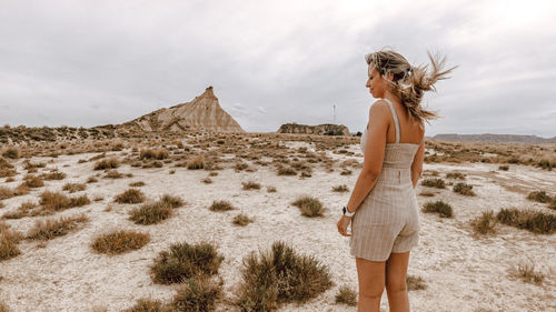 Side view of woman standing at desert against sky