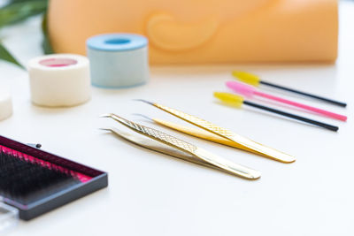 Close-up of false eyelashes with tweezers and curlers on table