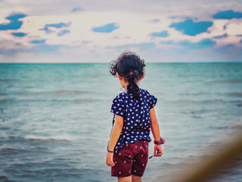 Girl with curly hair looking out at the sea