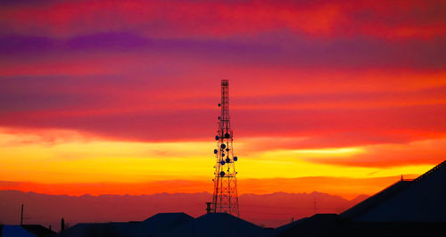 Low angle view of electricity pylon against sky during sunset