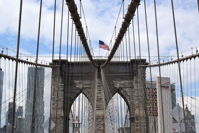 Low angle view of american flag on brooklyn bridge against sky