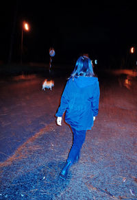 Man walking on illuminated road at night