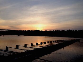 Pier on lake at sunset