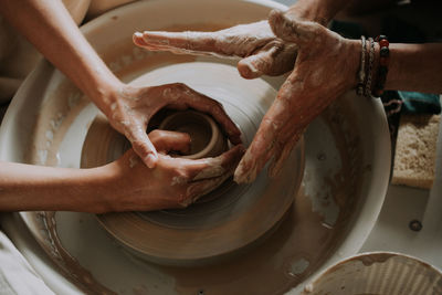 Potter teach teenage girl working with pottery wheel. top view. close up.