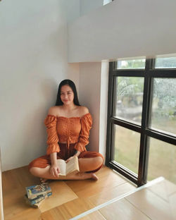 Portrait of young woman looking through window