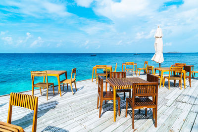 Chairs and table on beach against sky