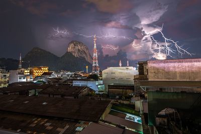 Panoramic view of illuminated city by lightning against sky at night